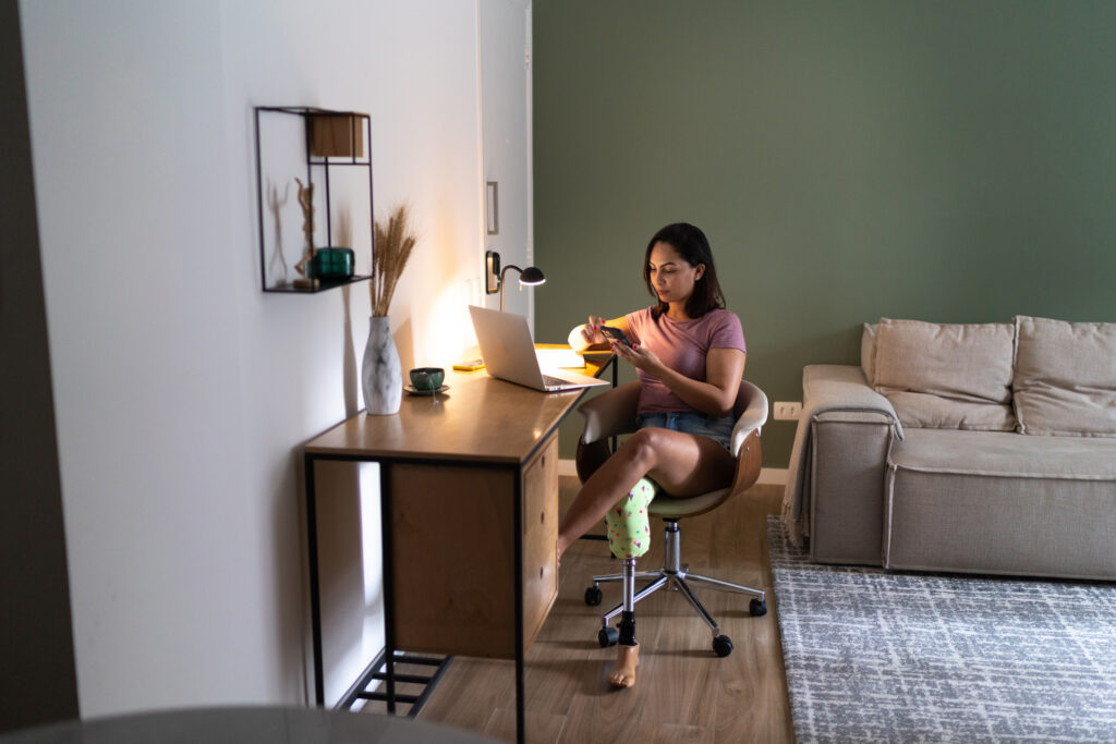 Young woman with disability using smartphone while working at home