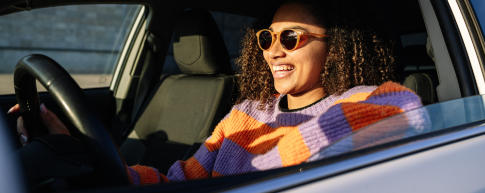 Young woman smiling with sunglasses driving in the car.