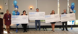 Representatives from local nonprofits pose with large donation checks.