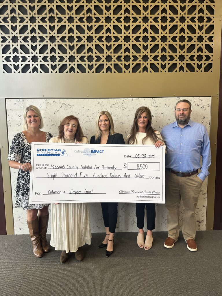 Women and men smiling with giant check written out to Macomb County Habitat for Humanity