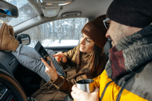 Family couple sitting in car in winter clothes iin snow forest, close up
