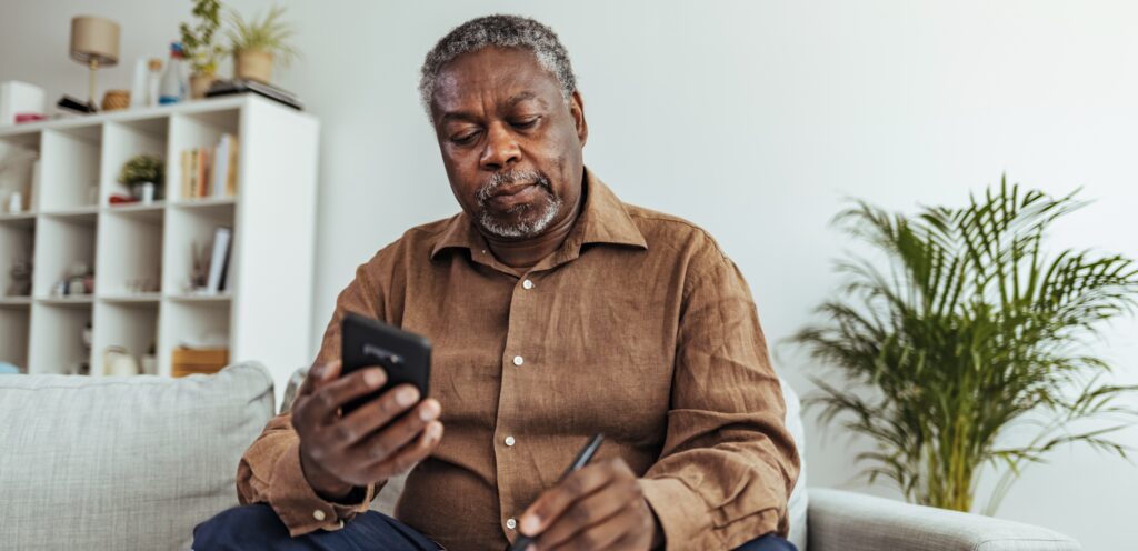 Older African American man on cell phone and writing a document
